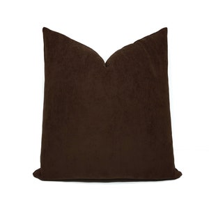 May include: A brown velvet pillow with a square shape and a smooth, soft texture.