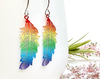 Puede incluir: Pendientes de plumas arcoíris con gancho plateado. Las plumas están recortadas y tienen un degradado arcoíris.