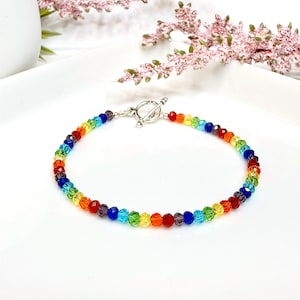 Könnte beinhalten: Ein Regenbogen-Kristallperlenarmband mit einem silbernen Toggle-Verschluss.