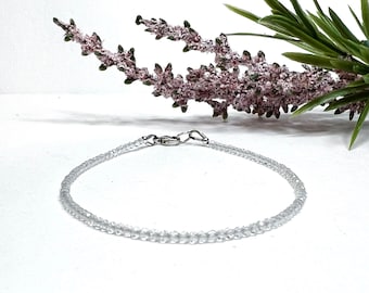Puede incluir: Un delicado brazalete de cuentas de cristal transparente con un cierre plateado.
