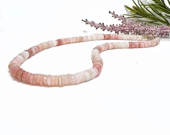 May include: A pink and white opal bead necklace with a gold clasp. The necklace is made of small, round beads that are strung together on a thin cord.