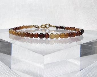 May include: A brown, gold, and clear gemstone bracelet with a gold clasp.