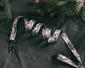 May include: A gray and black patterned dog leash with a black metal clip. The leash has a repeating pattern of bats and crescent moons.