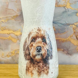 May include: A decorative glass vase featuring a watercolour-style image of a brown dog. The vase has a frosted, textured appearance with a crackle pattern. The dog's portrait is centered, showcasing its expressive eyes and fur.