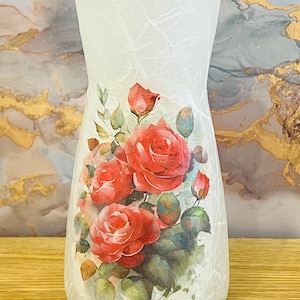 May include: White ceramic vase with a textured surface and a floral design featuring red roses and green leaves.