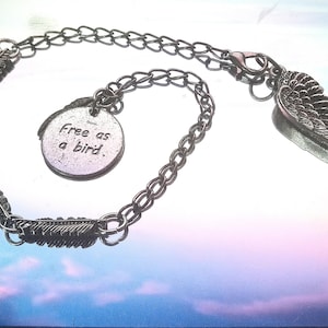 May include: A silver chain bracelet with a charm that says "Free as a bird" and a silver wing charm.