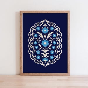 May include: A rectangular framed print featuring a dark navy blue background with a central symmetrical floral motif. The design consists of white scrolling vines and light blue flowers arranged within an ornate, pointed oval border.