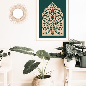 May include: A framed art print featuring an ornate floral design in shades of red, green, and beige against a dark teal background. The print is displayed on a white wall, alongside a woven basket with a large-leafed plant.