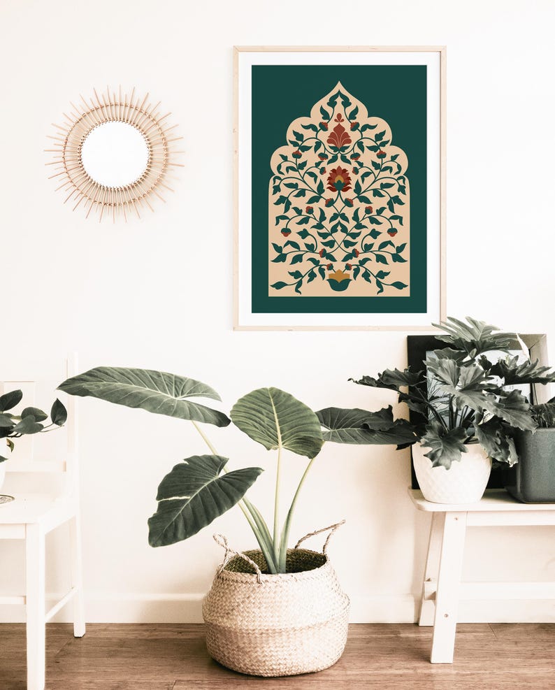 May include: A framed art print featuring an ornate floral design in shades of red, green, and beige against a dark teal background. The print is displayed on a white wall, alongside a woven basket with a large-leafed plant.