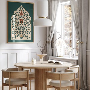 May include: A dining room scene featuring a round wooden table with four chairs. A framed artwork with a green background and floral design hangs on the wall. A white pendant light hangs above the table, and a window with sheer curtains is visible.
