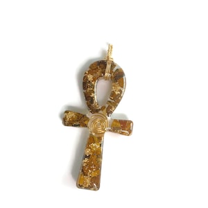 May include: Gold-toned Ankh pendant with a brown and gold resin design. The pendant is made with wire wrapped around the resin.