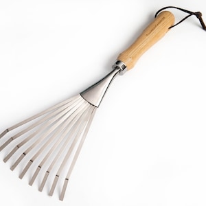 May include: A stainless steel garden rake with a wooden handle. The handle has a leather strap for hanging. The rake has 10 tines.