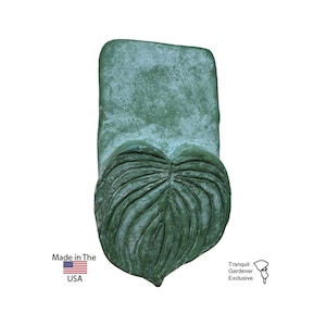 Könnte beinhalten: Eine grüne, herzförmige Wanddekoration aus Beton in Form eines Blattes. Das Blatt hat eine strukturierte Oberfläche. Die Dekoration wird in den USA hergestellt und ist exklusiv bei Tranquil Gardener erhältlich.