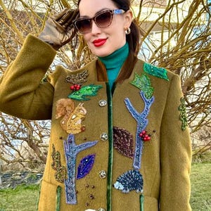 May include: A mustard yellow jacket with a velvet collar and embroidered woodland creatures. The jacket features a squirrel, a hedgehog, a rabbit, and leaves.
