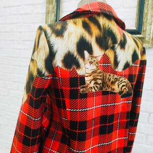 May include: A red and black plaid jacket with a leopard print collar and a cat print on the back.