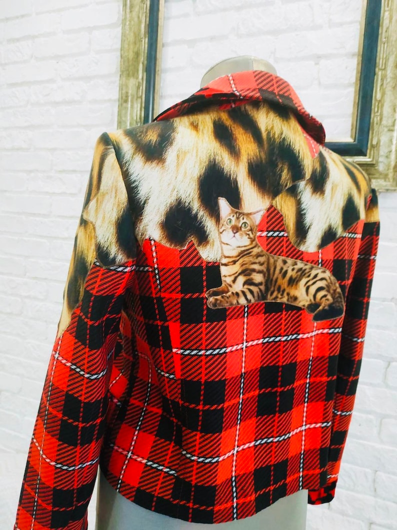 May include: A red and black plaid jacket with a leopard print collar and a cat print on the back.