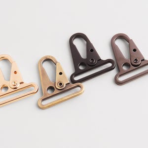 Puede incluir: Cuatro cierres giratorios metálicos en varios acabados: dorado, latón, marrón oscuro y bronce. Cada cierre tiene una base rectangular y un gancho curvo. Adecuado para bolsos, correas u otros proyectos de artesanía.