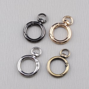 Puede incluir: Cuatro llaveros de metal con diferentes acabados: negro, plateado, dorado y latón antiguo. Cada anillo tiene un cierre giratorio y un pequeño bucle en la parte superior.