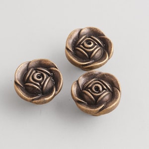 May include: Three antique bronze-colored rose-shaped cabinet knobs. Each knob features detailed petal and center designs. These decorative knobs are ideal for adding a vintage touch to furniture or cabinetry. The knobs are approximately 1.5 inches in diameter.