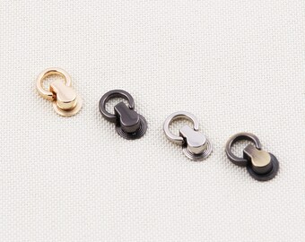 May include: Four metal purse hardware pieces in gold, black, silver, and bronze. Each piece has a ring attached to a rounded base. The hardware is designed for use in bag making and other craft projects.