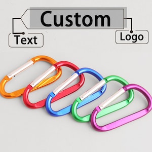 May include: A selection of brightly coloured carabiner clips in orange, red, blue, green, and purple. Each clip has a silver gate. The word "Custom" is displayed above the clips, with "Text" and "Logo" labels.