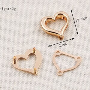 May include: Three rose gold-colored metal jewelry findings. One is a heart shape, approximately 0.79 inches wide and 0.73 inches tall. The second is a heart shape with three holes. The third is a geometric shape with three holes. The weight is 2g.