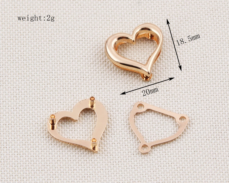 May include: Three rose gold-colored metal jewelry findings. One is a heart shape, approximately 0.79 inches wide and 0.73 inches tall. The second is a heart shape with three holes. The third is a geometric shape with three holes. The weight is 2g.