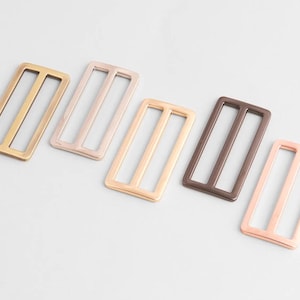 May include: Five metal rectangle sliders in various colors: gold, light pink, beige, brown, and rose gold. Each slider has three vertical bars. These sliders are used in bag making and other crafts.