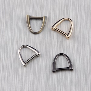 Könnte beinhalten: Vier D-Ringe aus Metall in verschiedenen Ausführungen: Antikmessing, Gold, Silber und Schwarz.