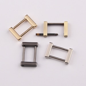 Pode incluir: Quatro fivelas de metal em forma de D em diferentes acabamentos: dourado, prateado, preto e latão antigo. As fivelas são retangulares com uma pequena abertura no centro.
