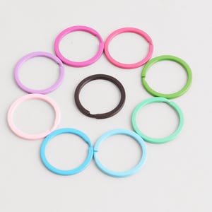 Peut inclure: Un ensemble de porte-clés colorés dans diverses teintes, notamment rose, violet, vert, bleu et marron. Les porte-clés sont disposés en cercle, offrant une présentation vibrante et organisée.