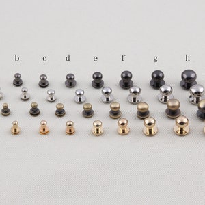 May include: An assortment of metal rivets in different sizes and finishes, such as silver, gold, and black. The rivets feature a rounded head and a flat base, ideal for leatherwork or clothing.