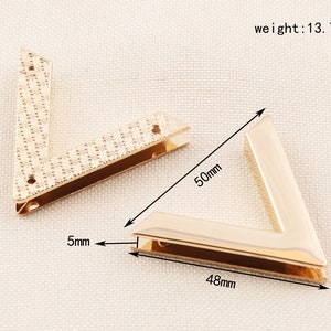 May include: Two gold-colored, V-shaped metal corner brackets. One bracket is 50mm long, 48mm wide, and 5mm thick. The other bracket has a textured pattern. The weight of the brackets is 13.7g.