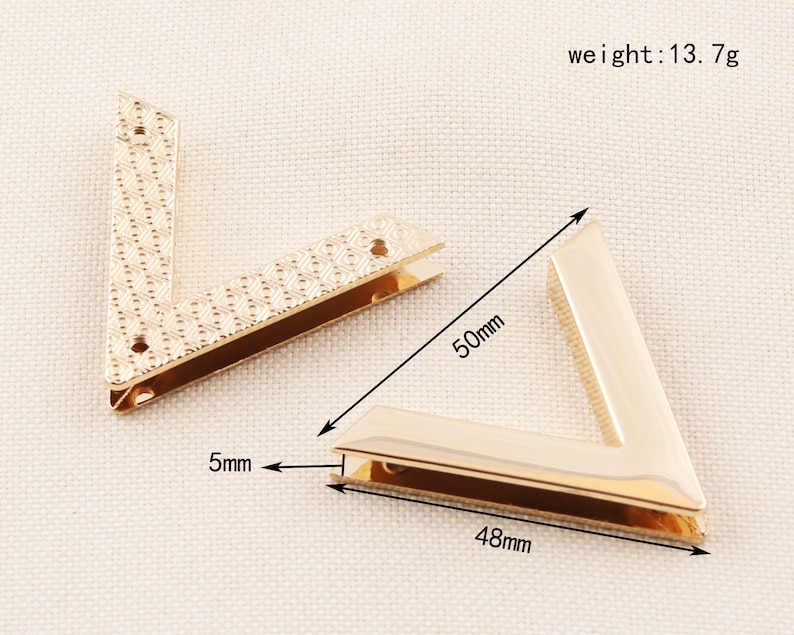 May include: Two gold-colored, V-shaped metal corner brackets. One bracket is 50mm long, 48mm wide, and 5mm thick. The other bracket has a textured pattern. The weight of the brackets is 13.7g.