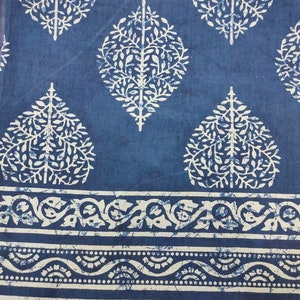 May include: Blue fabric with a white floral pattern. The fabric has a border with a white floral design.