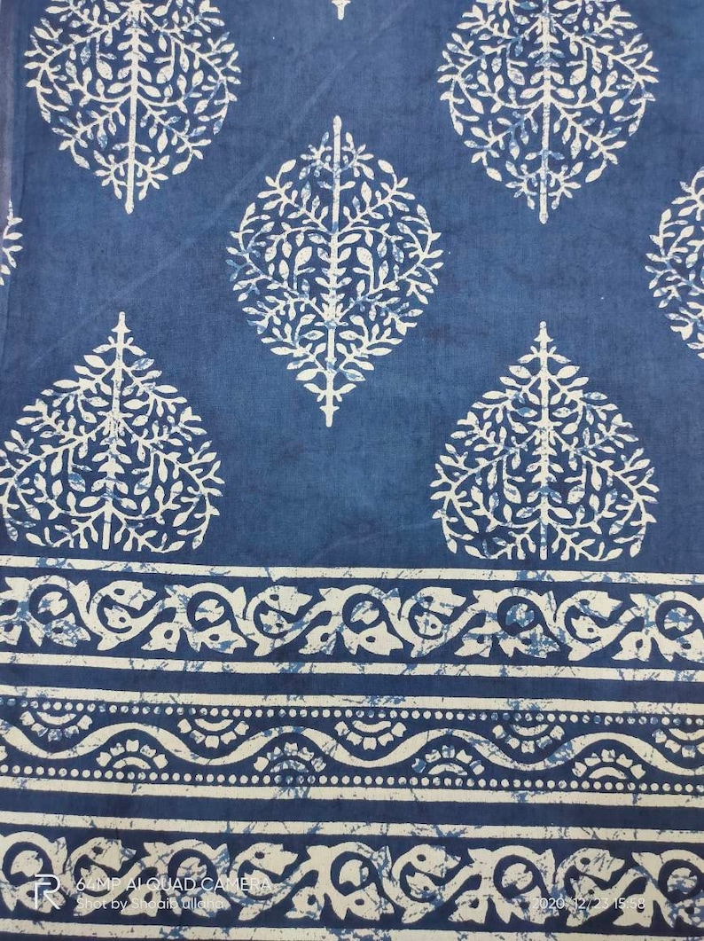 May include: Blue fabric with a white floral pattern. The fabric has a border with a white floral design.