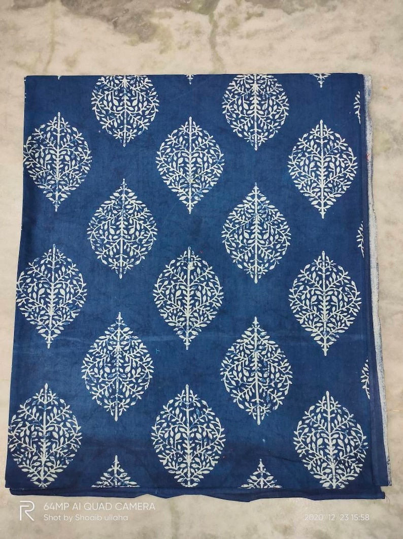 May include: Blue cotton fabric with a white leaf pattern. The fabric is folded in half and has a white border.