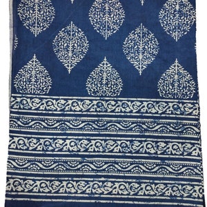 May include: A blue cotton fabric with a white floral pattern. The fabric has a border with a white wave design.