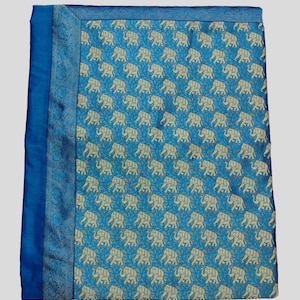 May include: A blue throw blanket with a white elephant pattern. The blanket has a blue border.