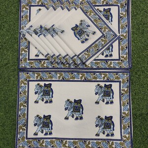 May include: A set of white placemats and napkins with a blue and gold floral border and elephant motif. The napkins are folded and stacked, and the placemats are rectangular. The elephant design is repeated across the set.
