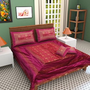 May include: A magenta velvet bedspread with gold embroidery and a matching set of pillowcases and throw pillows. The bedspread has a decorative border with a floral pattern.