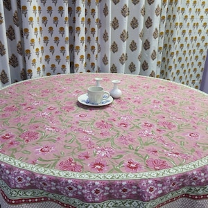 May include: A pink and green floral round tablecloth with a scalloped edge. The tablecloth has a white border with a green and pink floral pattern.