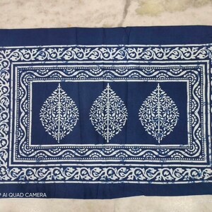 May include: A blue cotton pillowcase with a white floral pattern. The pattern features three stylized leaves with intricate details. The pillowcase has a white border with a repeating floral design.