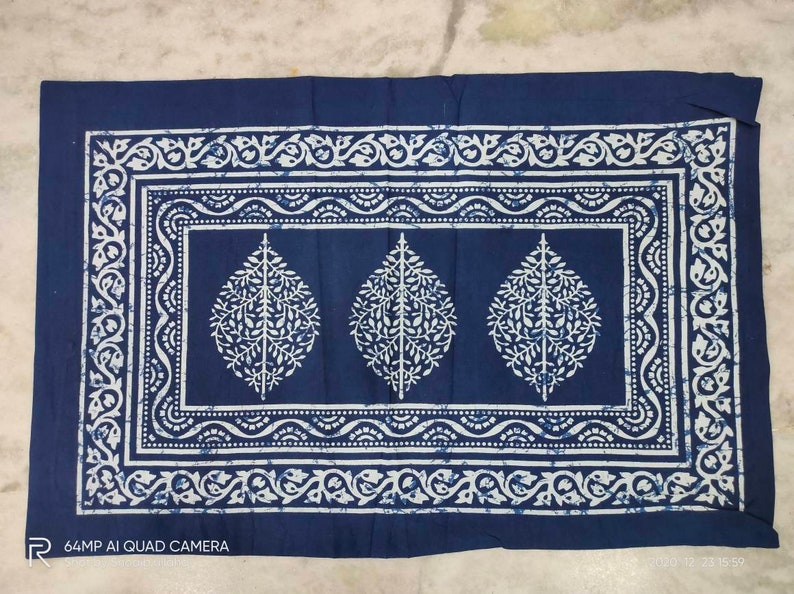 May include: A blue cotton pillowcase with a white floral pattern. The pattern features three stylized leaves with intricate details. The pillowcase has a white border with a repeating floral design.