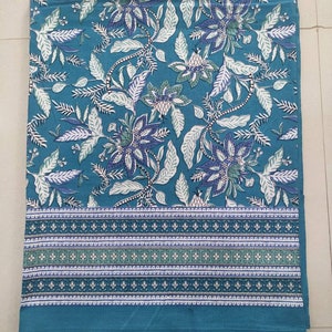 Puede incluir: Una sábana de cama de algodón azul con un patrón floral blanco y un borde de rayas blancas, azules y verdes.