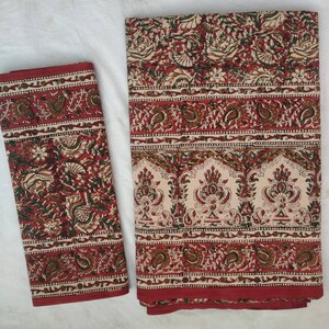 May include: A set of two red and cream cotton bed sheets with a floral and paisley print. The sheets are folded and ready to be used.
