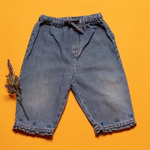 Könnte beinhalten: Eine blaue Jeans-Shorts mit Kordelzugbund und gerafftem Saum. Die Shorts liegen flach auf einem gelben Hintergrund.