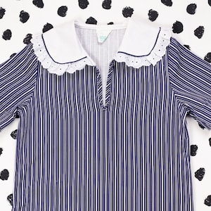 May include: A blue and white striped short-sleeved dress with a white collar and lace trim.