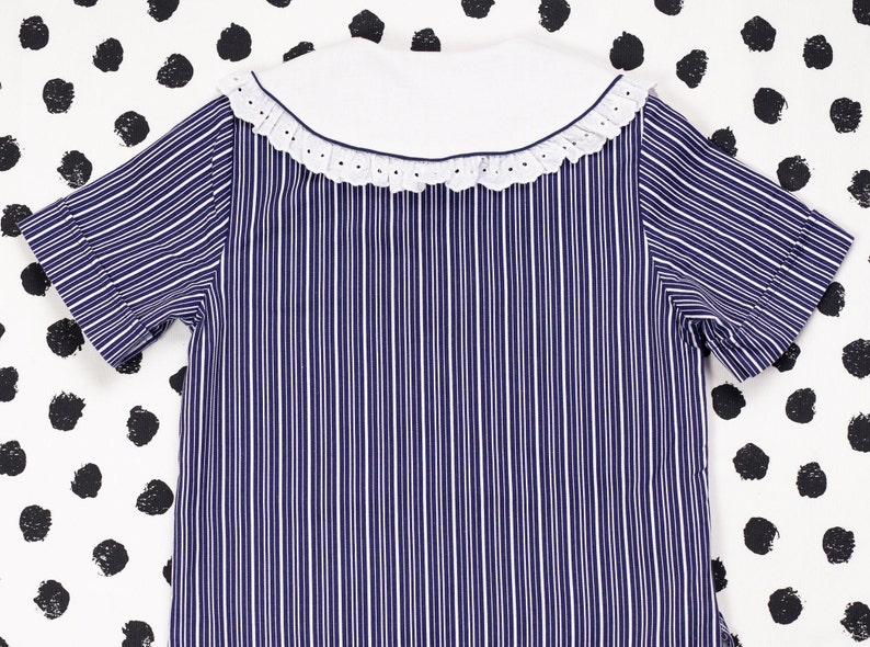 May include: A blue and white striped short-sleeved shirt with a white collar and a lace trim.