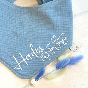May include: A light blue bandana with the text "Hades Big Brother" in white cursive lettering and a small heart symbol.